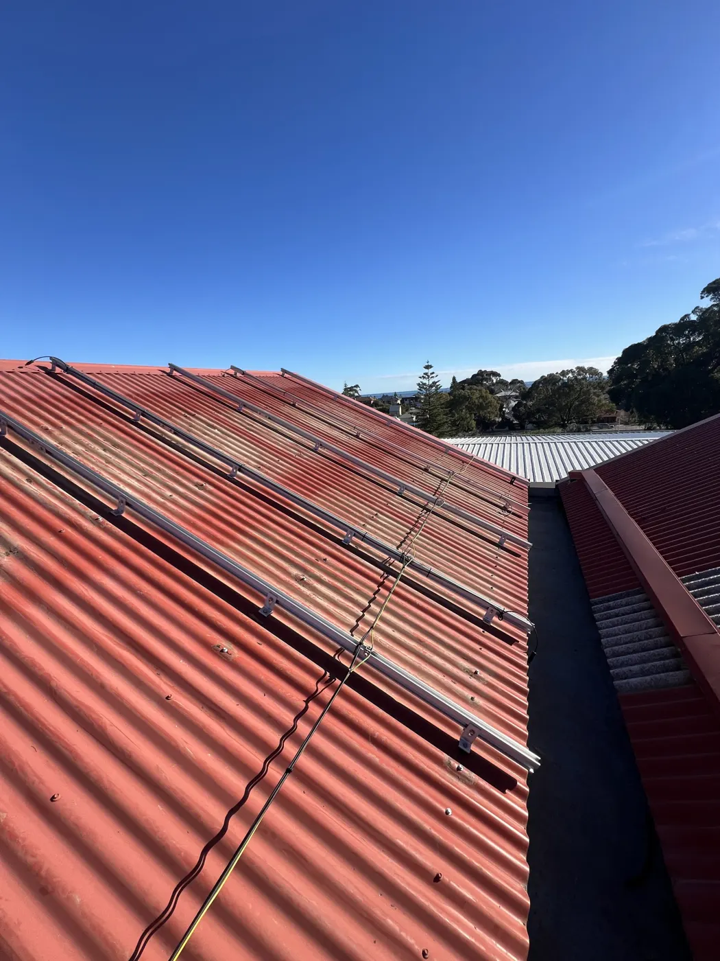 Solar rails installed on the red Colorbond roof