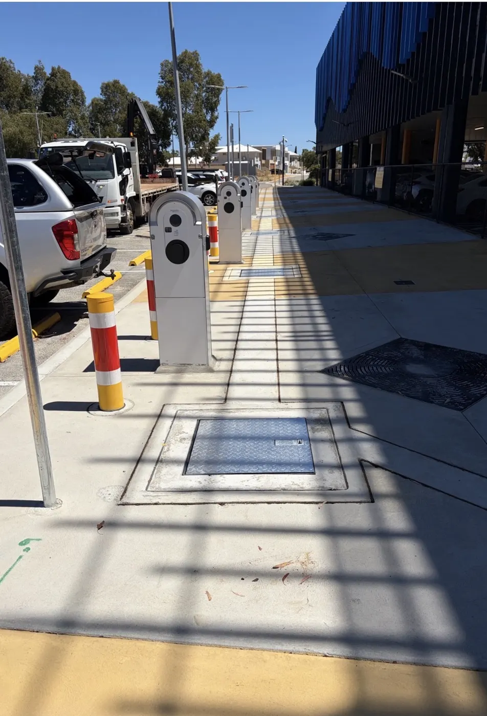 Row of finished EV chargers with bollards along the Mandurah Station car park footpath