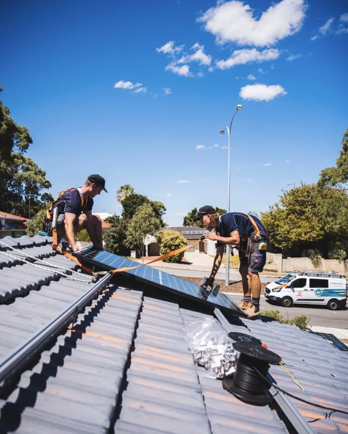 Two Infinity electricians installing solar panels on a tiled roof